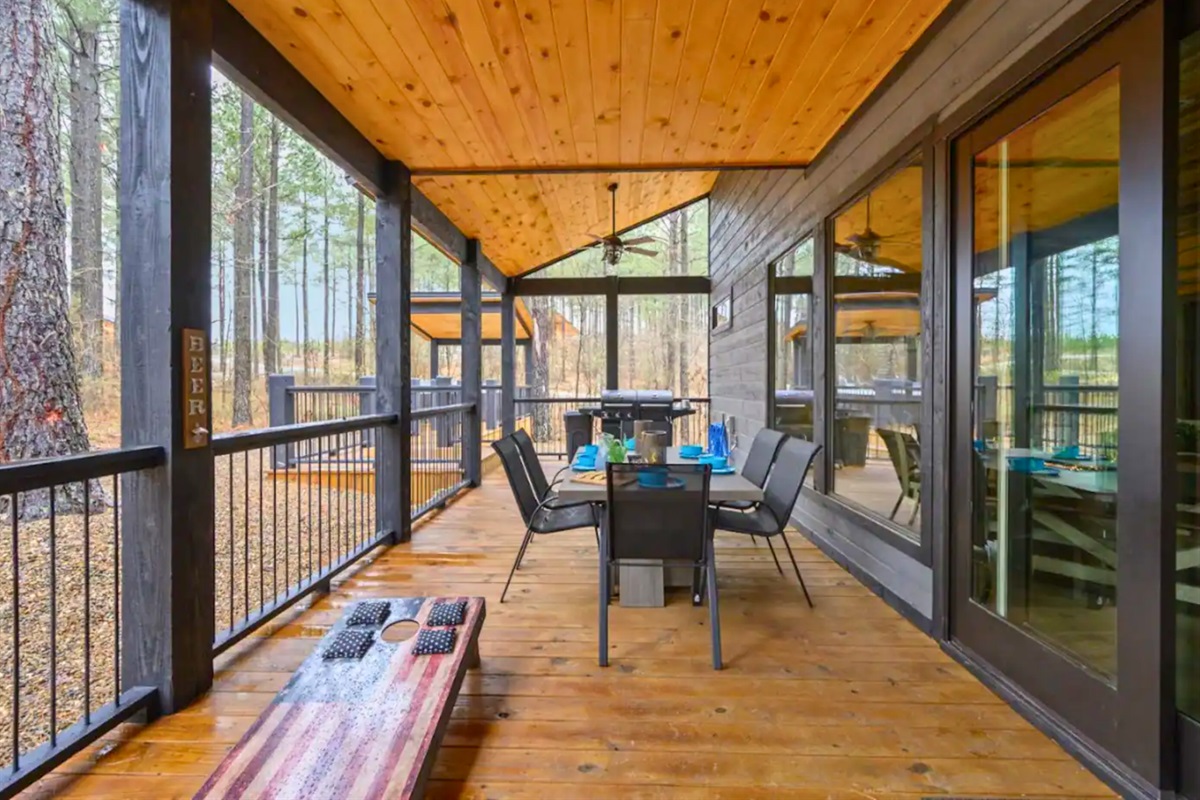 Spacious porch with a wooden dining set overlooking a serene forest backdrop.