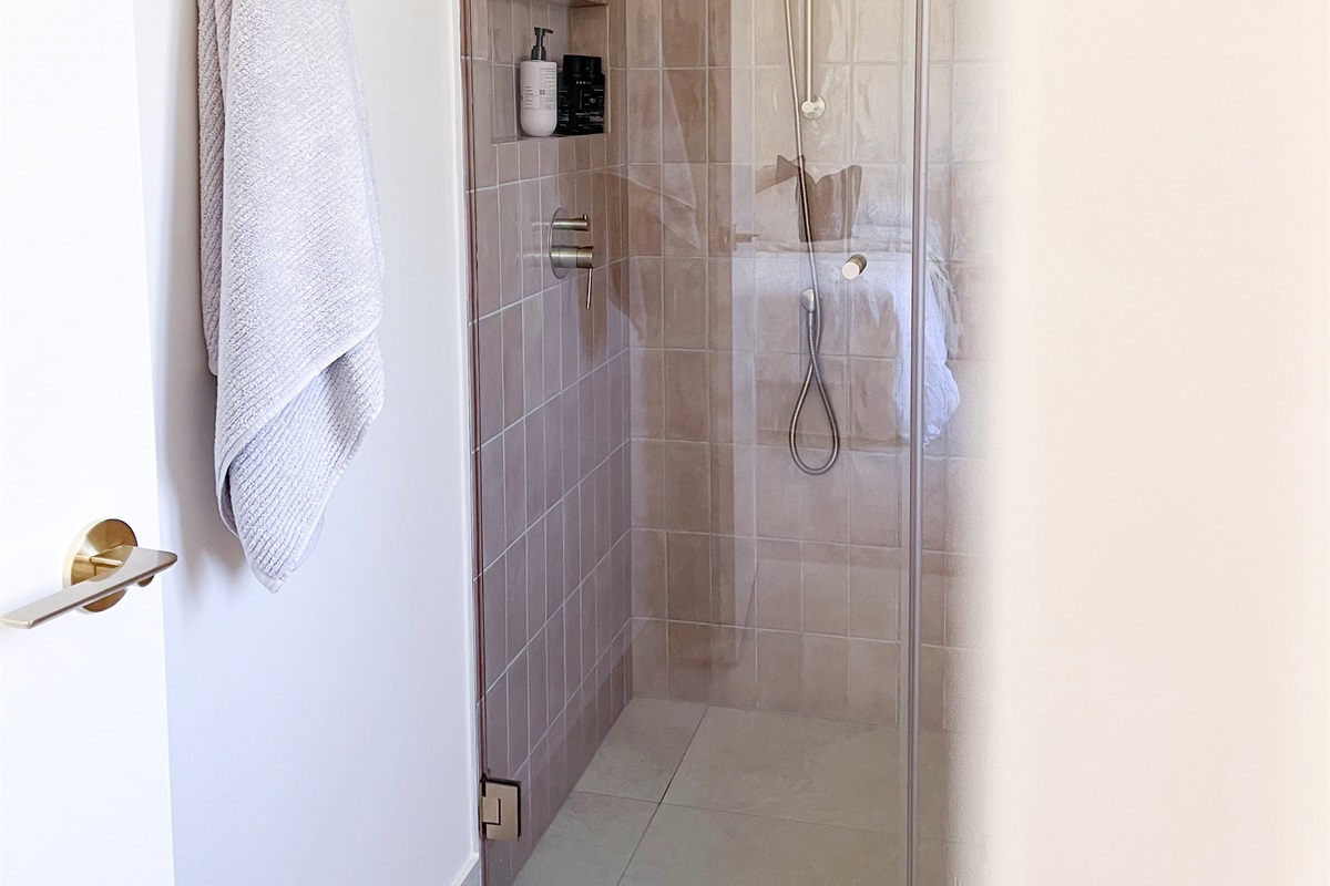 The walk-in shower has a glass screen, tiled walls and simple shelf space, keeping the bathroom easy to use during longer stays.