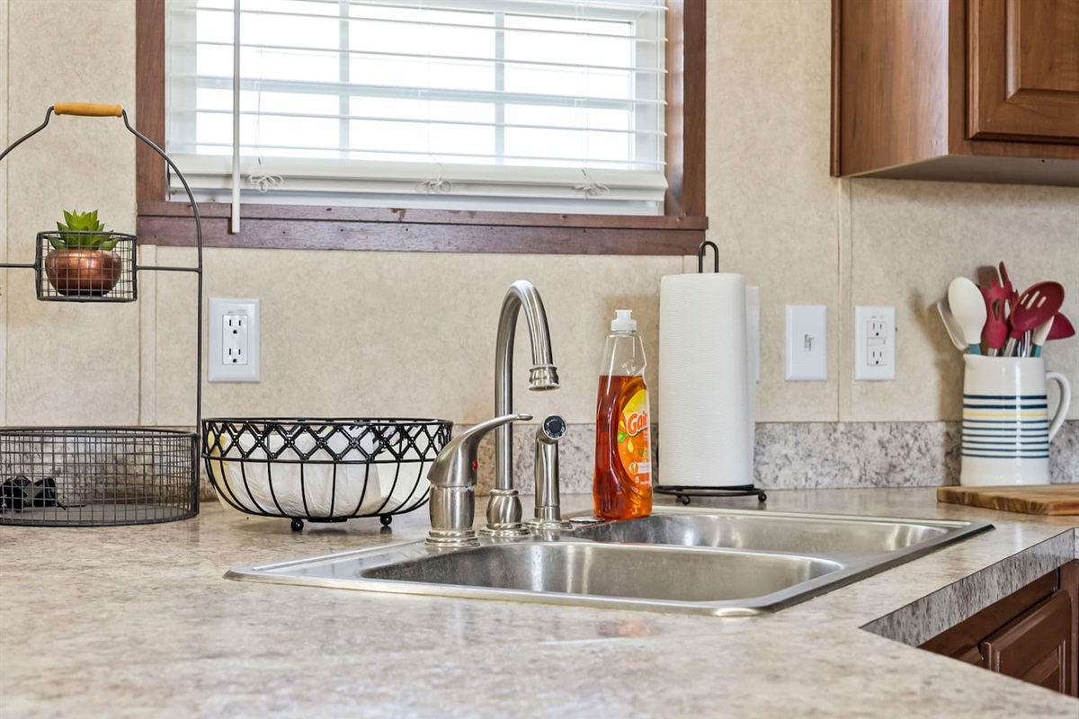 Bright kitchen sink area with natural light, double basin, and plenty of counter space for meal prep and cleanup.
