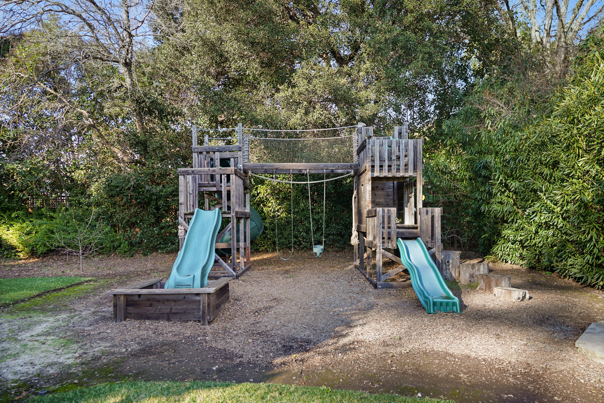 A family-friendly backyard designed for fun and relaxation, featuring a private playground where kids can climb, slide, and play while adults unwind nearby. With plenty of outdoor space to gather, this backyard is perfect for making lasting family memories
