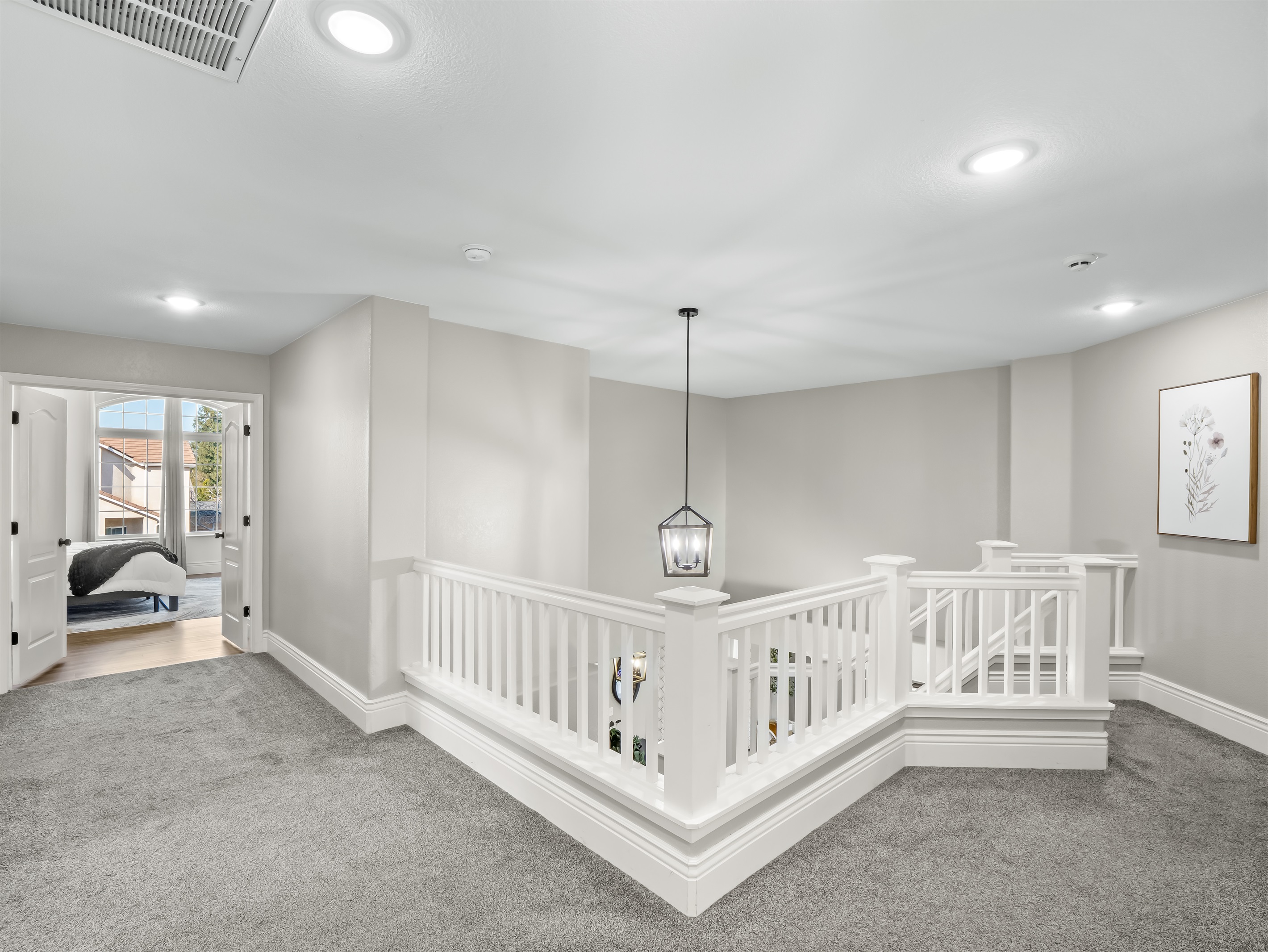 Bright upper-level loft area with elegant railing detail and designer lighting—an airy overlook that enhances the home’s dramatic open-concept design.