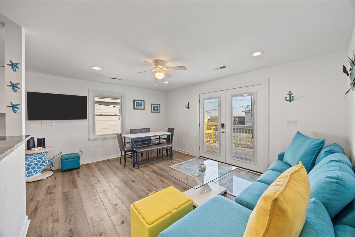 Open-concept living and dining space with coastal touches, comfy seating, and easy access to the balcony