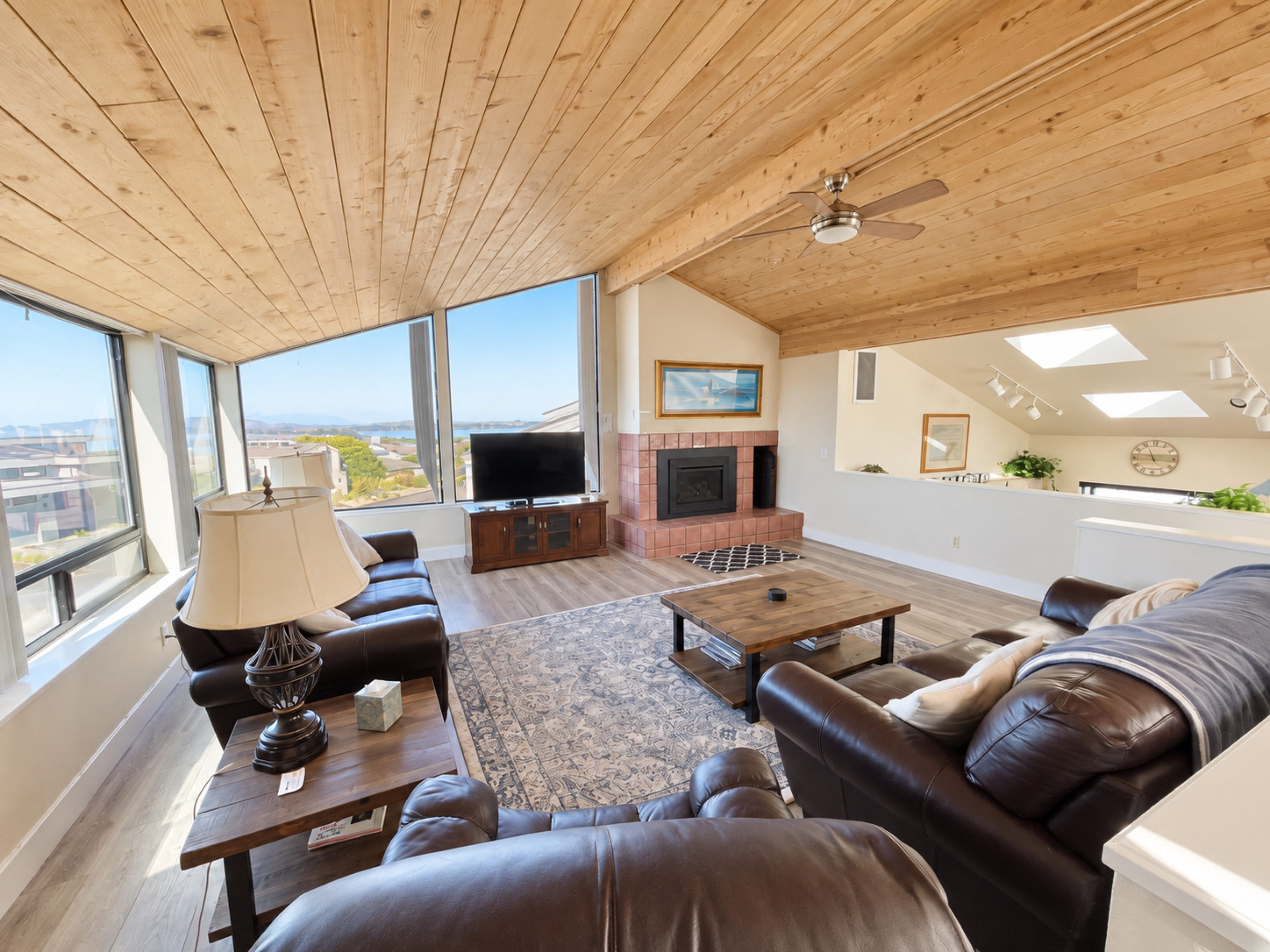Living Room with comfortable leather furnishings, large picture windows overlooking the beach/ocean. Tall vaulted ceilings. Propane fireplace. Large screen HDTV with Roku/cable..