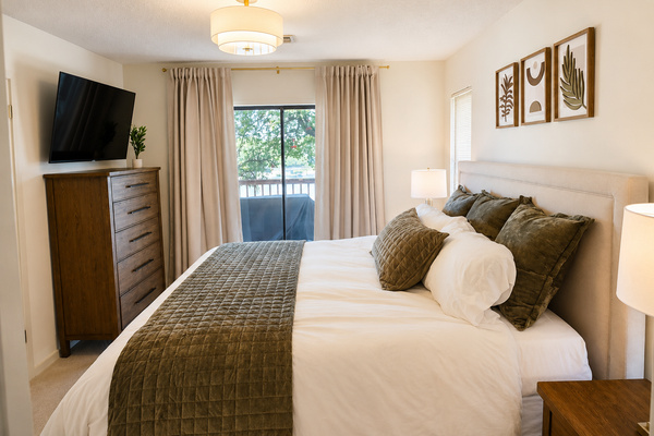 King bedroom with television, direct deck access, and lake view.