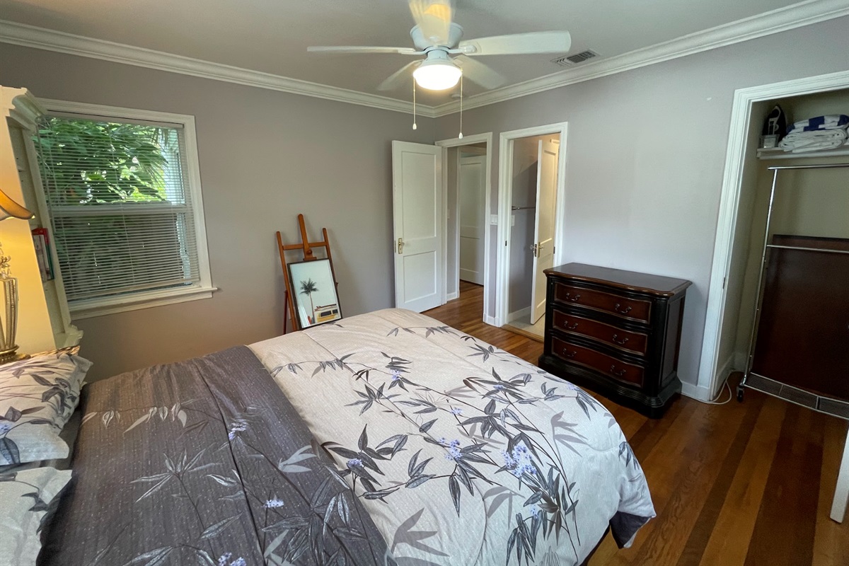 The second bedroom features a queen-zied bed and a stylish painter's floor stand.