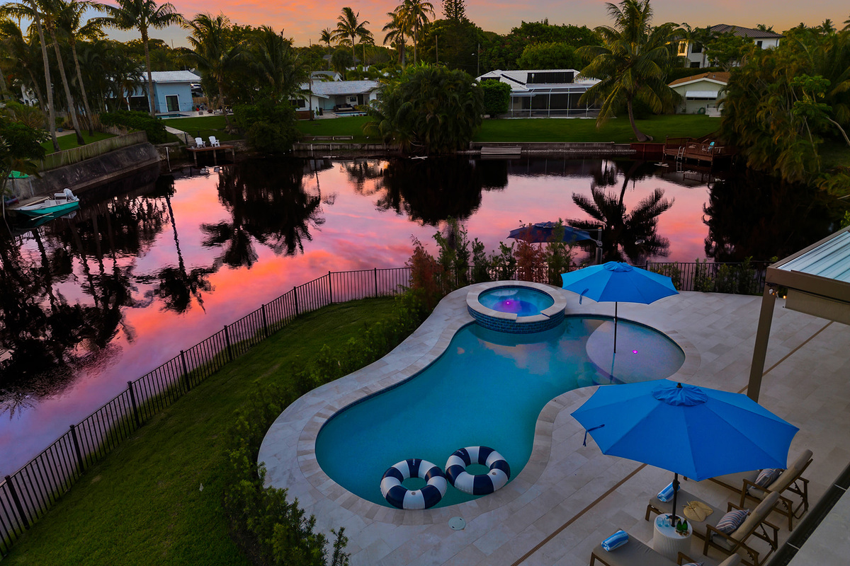 Aerial view showcasing the home's expansive outdoor living spaces, private pool, and waterfront location.