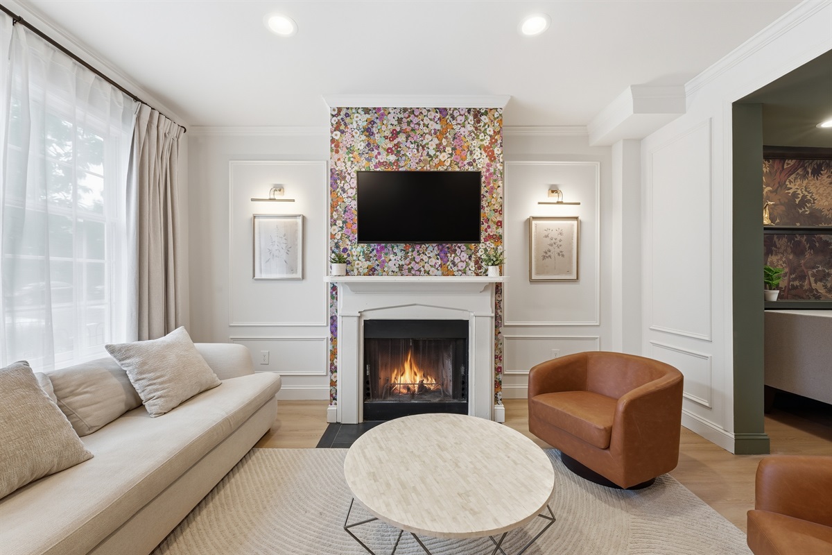 Elegant sitting room with designer floral accent wall, cozy decorative fireplace, and comfortable lounge seating — the perfect place to unwind after exploring Capitol Hill. (Fireplace is decorative only)