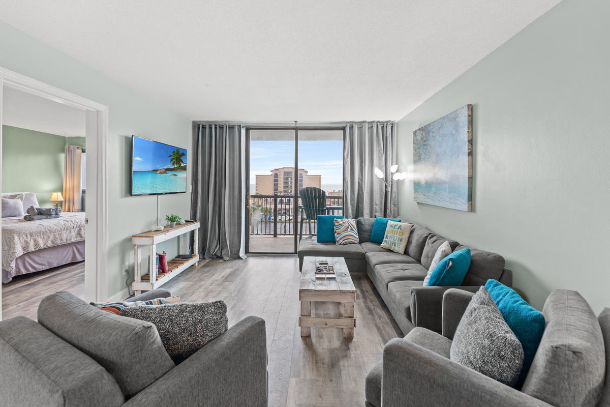 Comfy living room area with large TV and balcony access