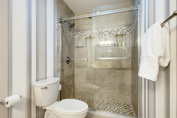 The renovated primary bath features a spacious tiled walk-in shower with frameless glass doors.