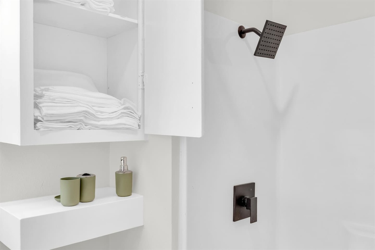 Bathroom with shower/tub combo, fresh linens, rainfall shower head and hotel-style touches.