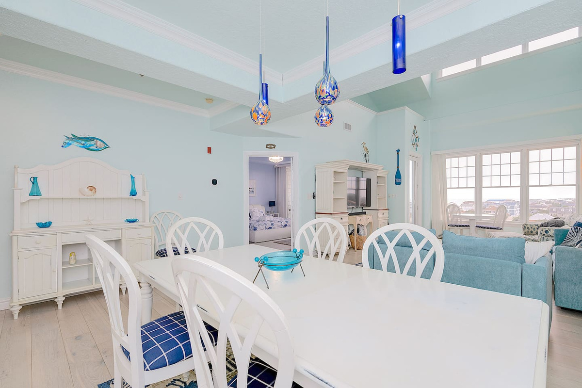 Bright and airy open-plan living and dining area with coastal decor – perfect for family meals and relaxing while enjoying ocean views through the large windows.