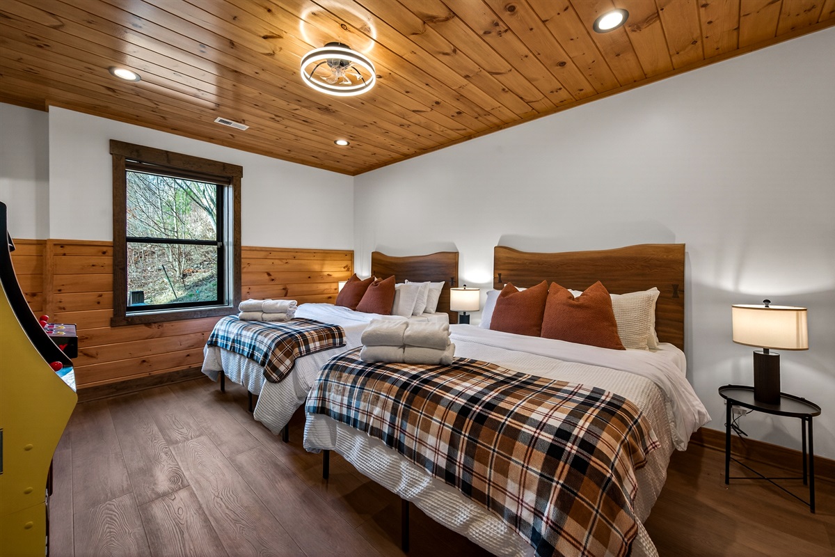 Double Queen Suite – This comfortable bedroom features two queen beds, a large TV, 2 arcades and a private en-suite bathroom with a bathtub, offering a relaxing and fun retreat after a day exploring the Smoky Mountains.