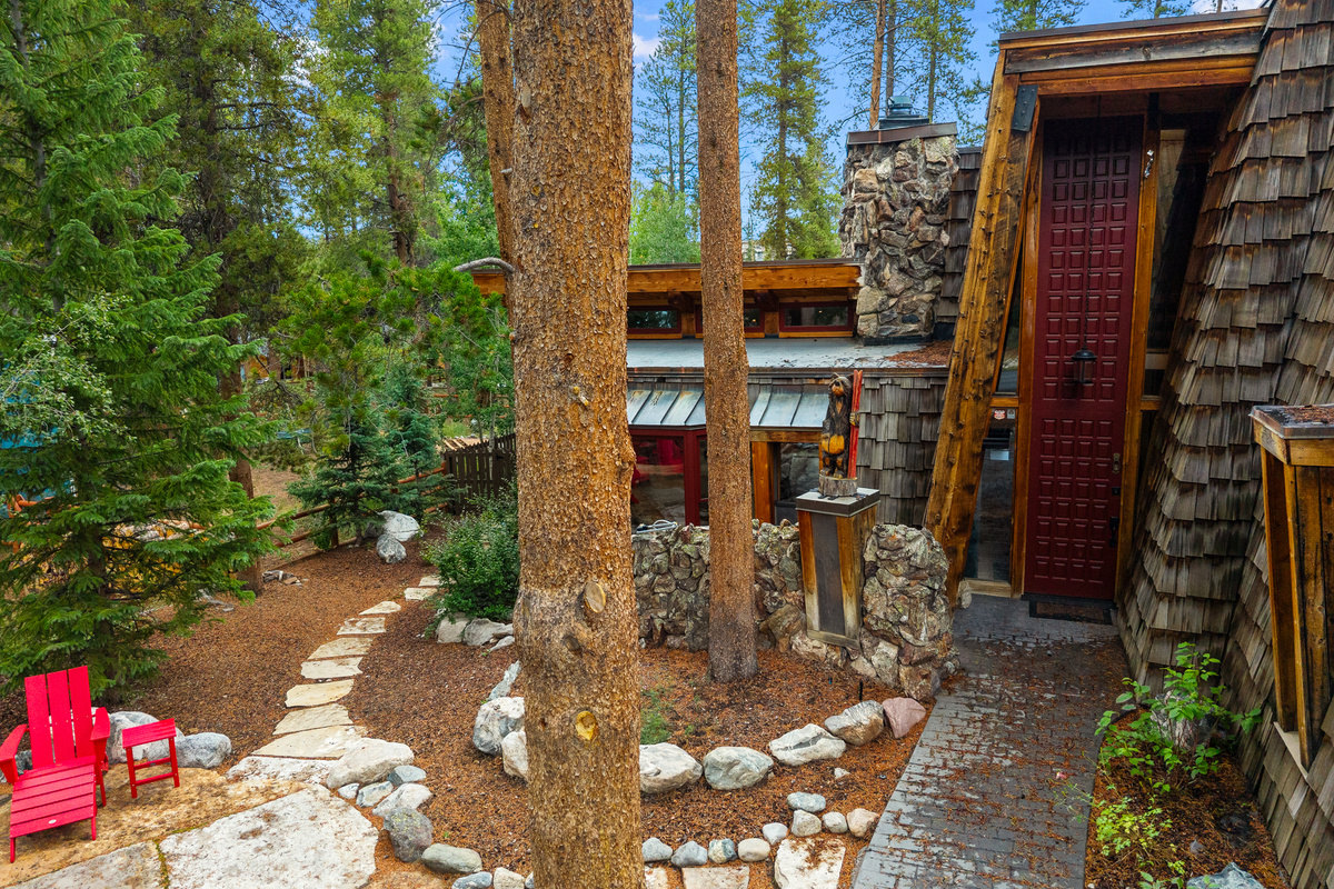 Summer front exterior with soaring lodgepole pines and rustic landscape