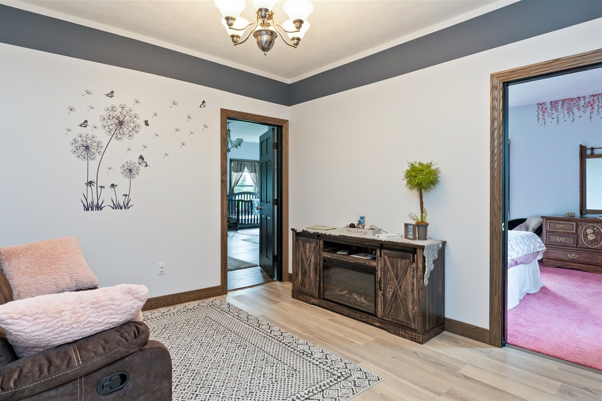 Cozy upstairs common area featuring a plush recliner sofa, soft accents, and modern flooring, ideal for relaxing evenings at home.