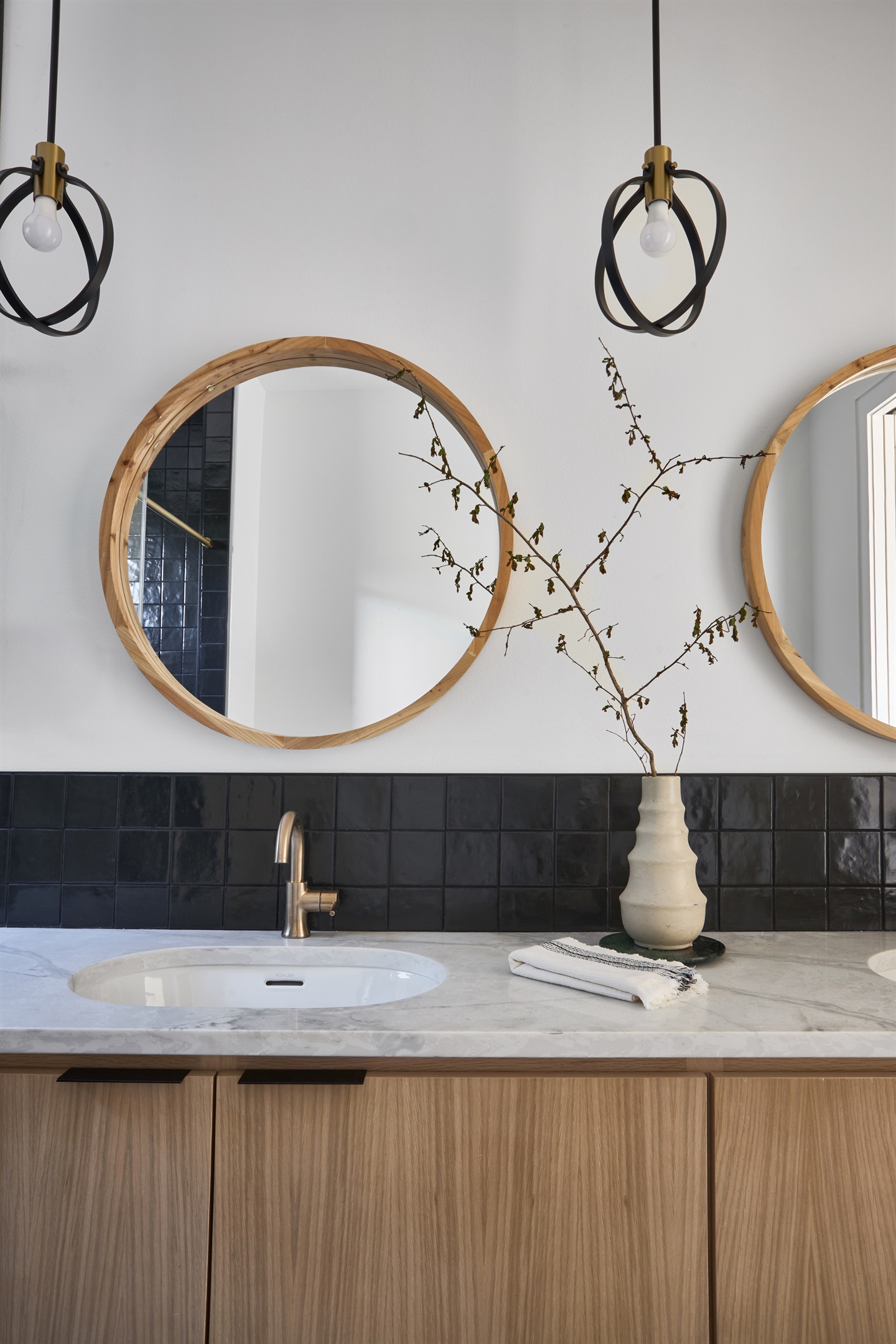 One of four stylish en-suite bathrooms, featuring dual vanities, bold black tile, and brass fixtures for a spa-like retreat.
