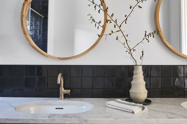 One of four stylish en-suite bathrooms, featuring dual vanities, bold black tile, and brass fixtures for a spa-like retreat.