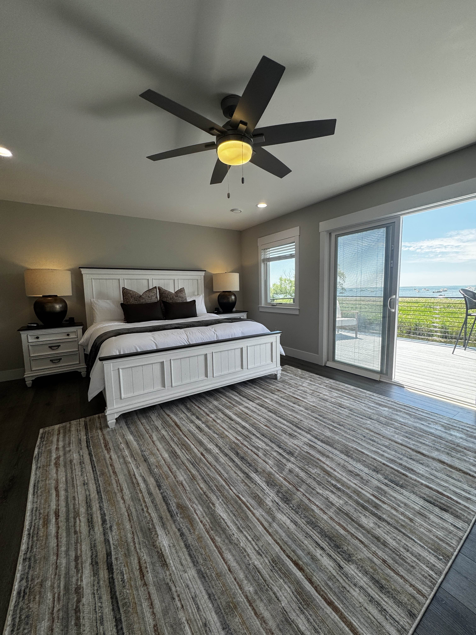 Bright and spacious bedroom with a king bed, modern furnishings, and private balcony access offering serene waterfront views—perfect for a relaxing stay.