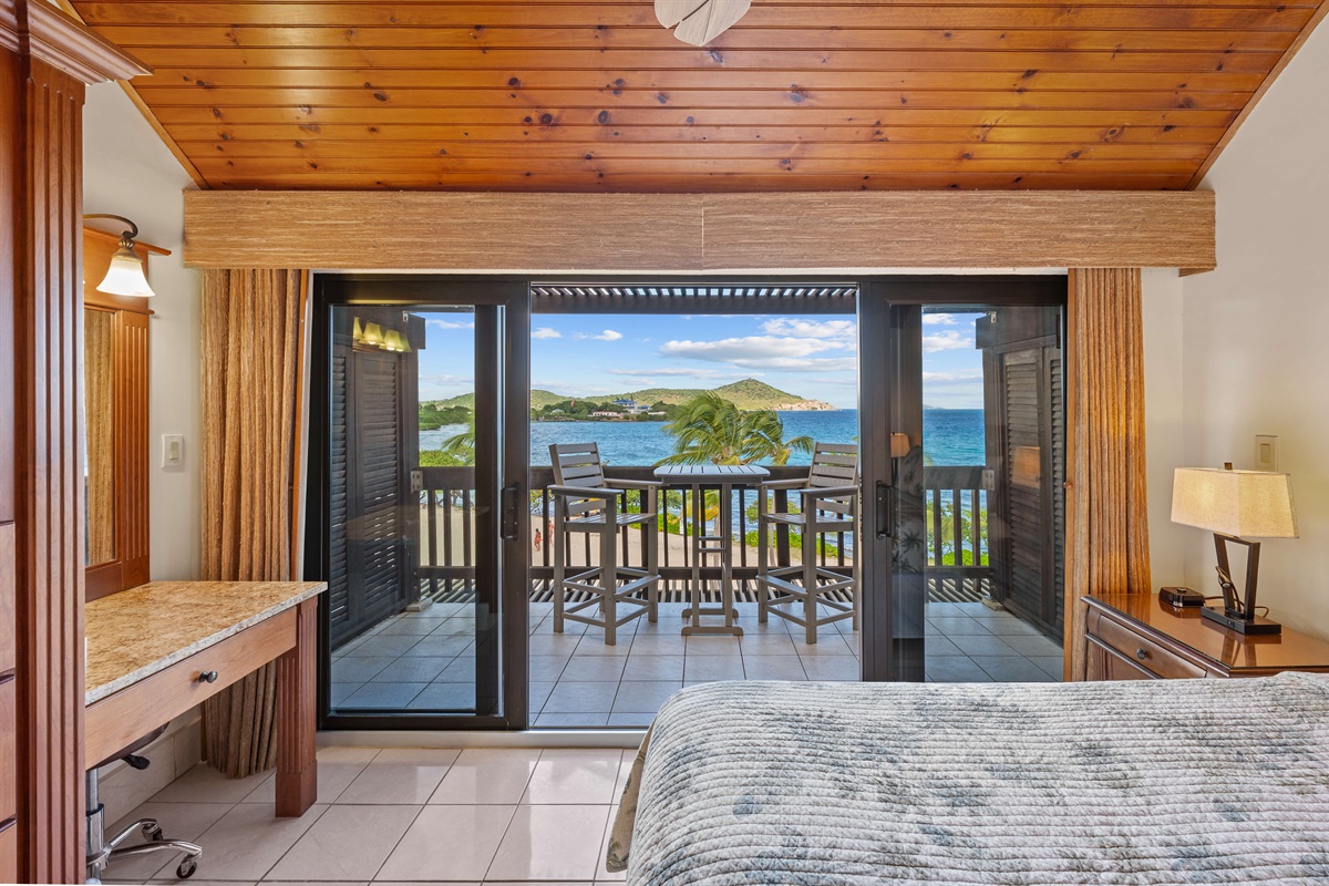 Primary bedroom with Queen bed, ceiling fan, TV and balcony