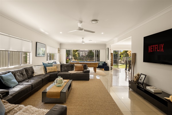 Spacious open-plan living area with multiple seating zones flowing seamlessly to the waterfront Alfreso terrace and pool.