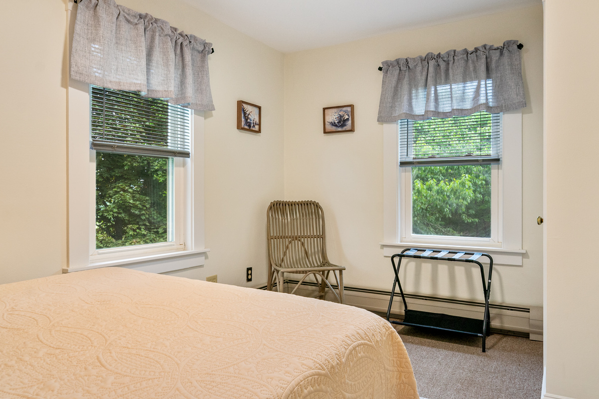 Unpack your bags onto the convenient luggage rack and feel yourself settle into the slow rhythm of the home. Natural light streams past the woven wicker corner chair, offering a peaceful, private pocket to read or watch the trees sway outside.