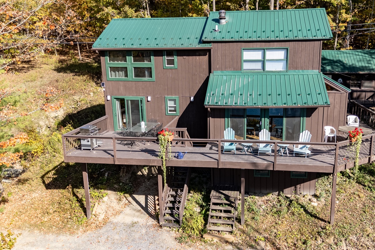 Deck view showing outdoor seating area overlooking trees and hint of lake.