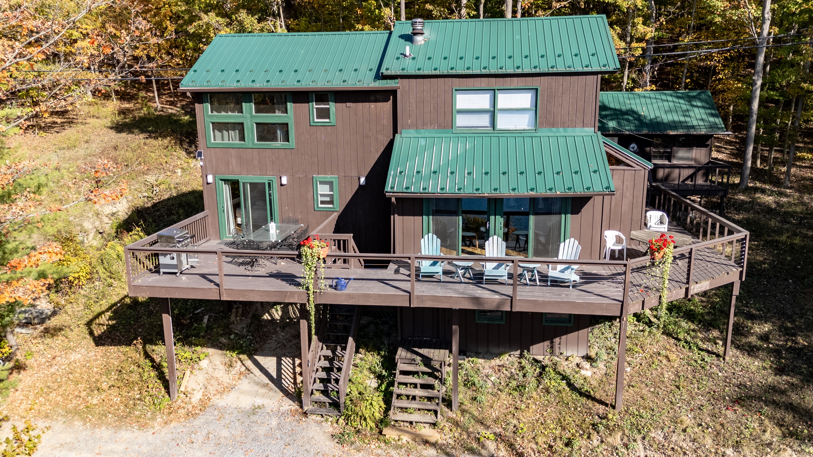 Deck view showing outdoor seating area overlooking trees and hint of lake.