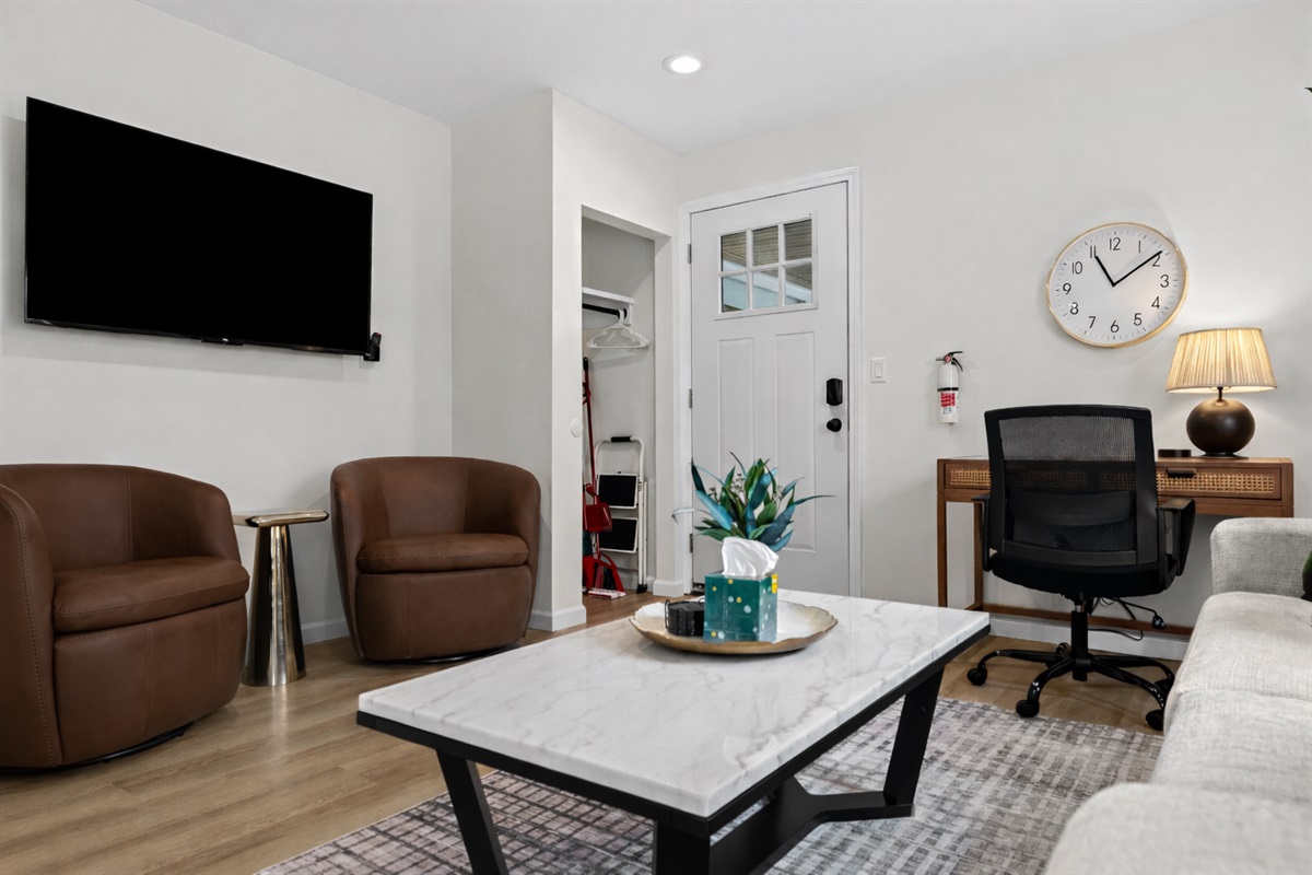 Inviting living space with smart TV, cozy seating, and a dedicated work desk—bright, functional, and perfect for relaxing or staying productive.