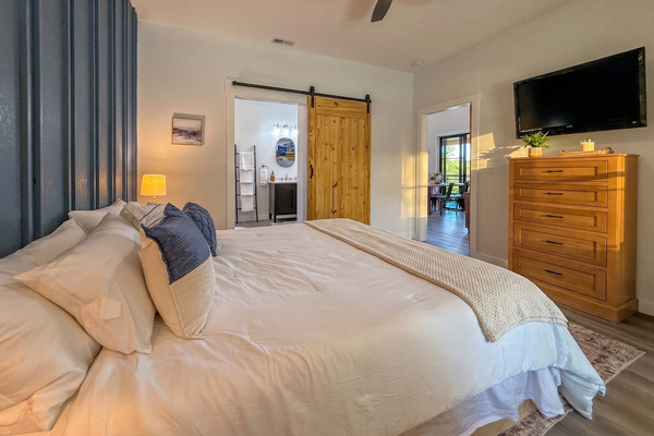Primary suite with smart TV and sliding barn door, the private hot tub is just outside.
