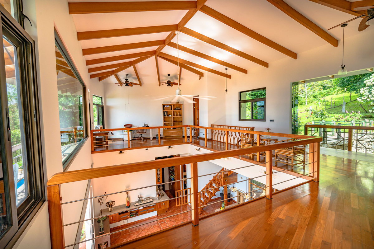 Second-floor primary suite — open loft layout with soaring wood beam ceilings and panoramic views