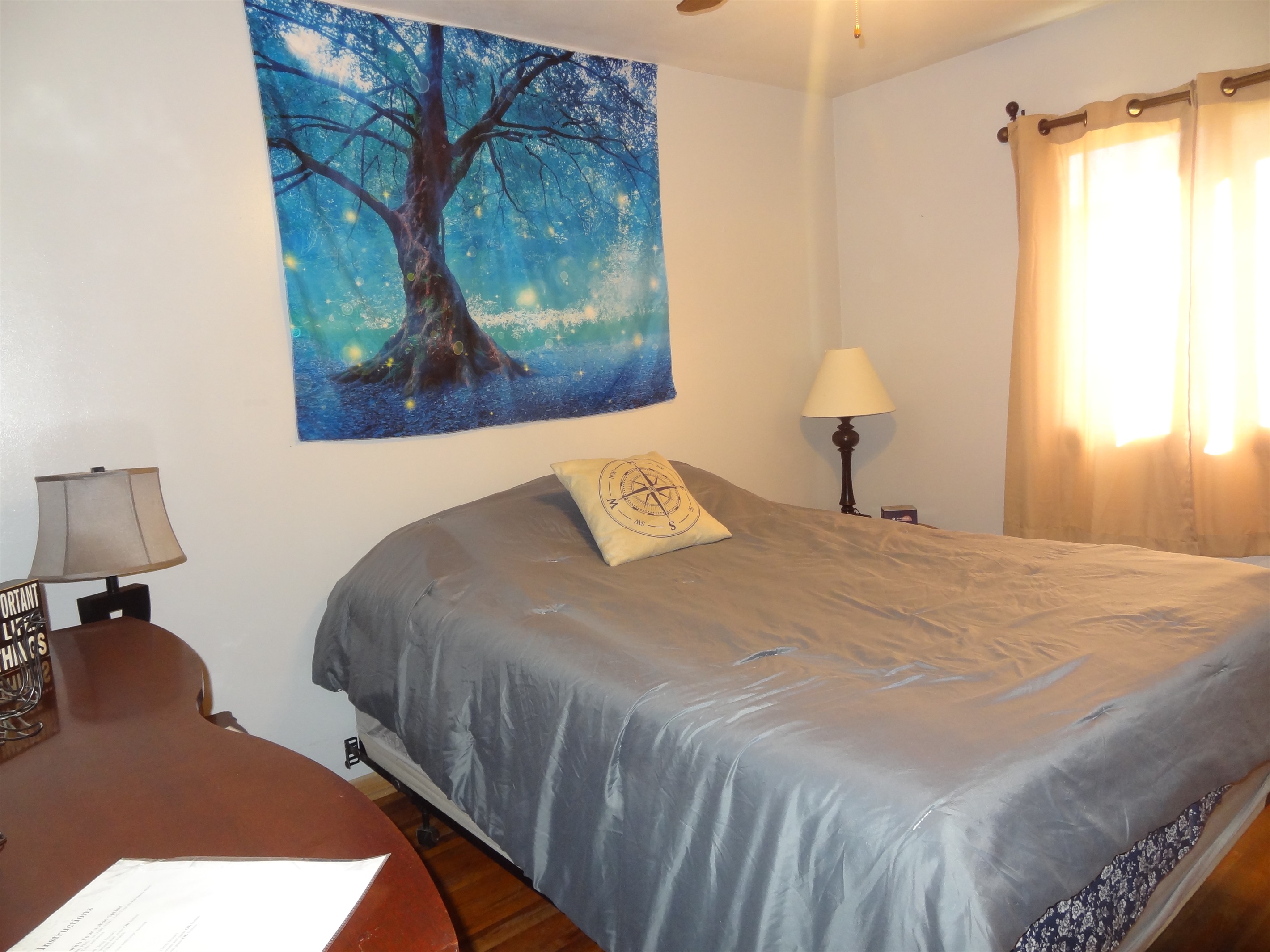 Master bedroom with queen bed, Roku smart TV, dresser, ceiling fan, and desk
