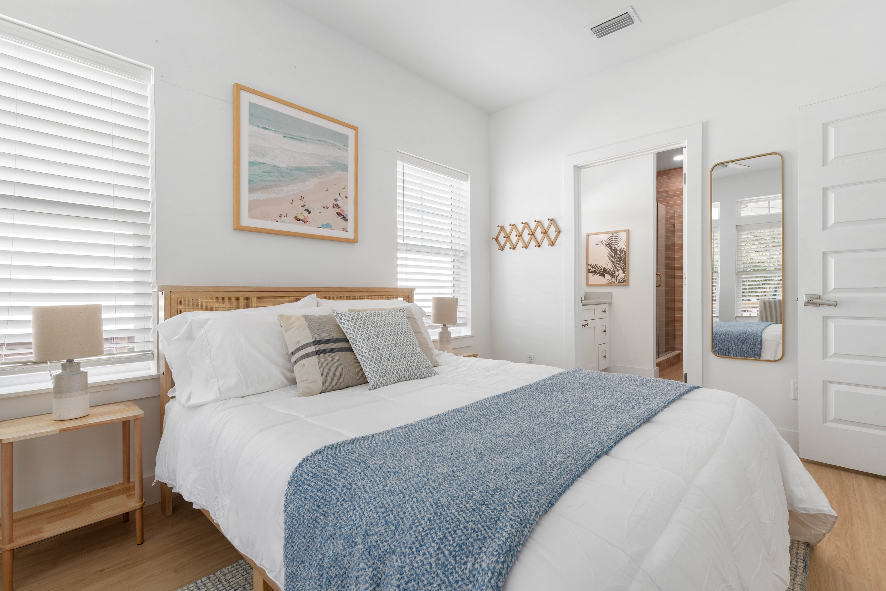 Your own bathroom through that door, which in a full house is worth more than square footage. Beach art over the bed, a mirror by the closet, and lamps on both sides for readers keeping different hours.