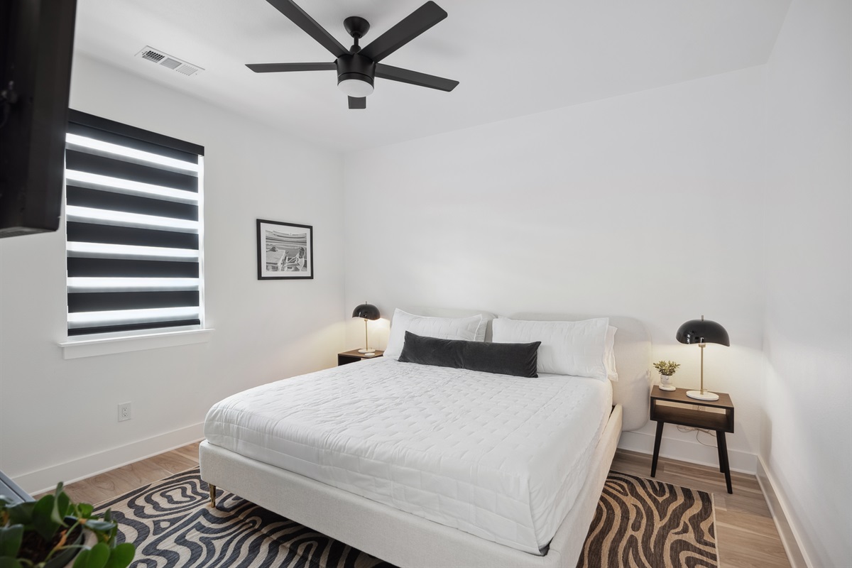 A tranquil room featuring a king-sized bed, elegant decor, and a smart TV, providing both comfort and simplicity. Enjoy a restful sleep with our room-darkening shades.