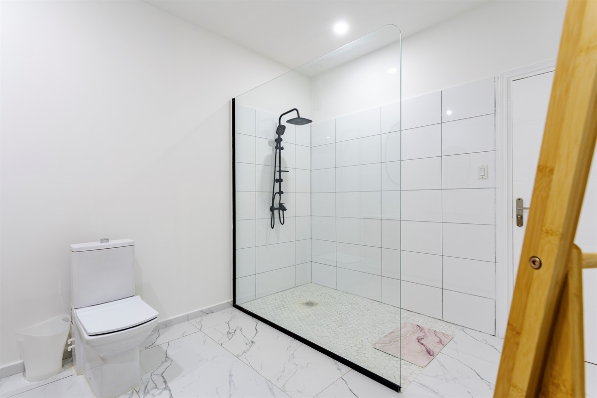 Rainfall shower with clean tilework and glass enclosure in the primary en-suite bathroom