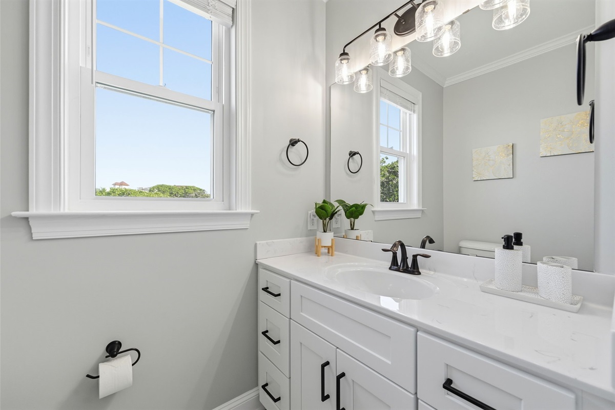 Clean and stylish vanity area with natural light, sleek fixtures, and thoughtful touches throughout the space