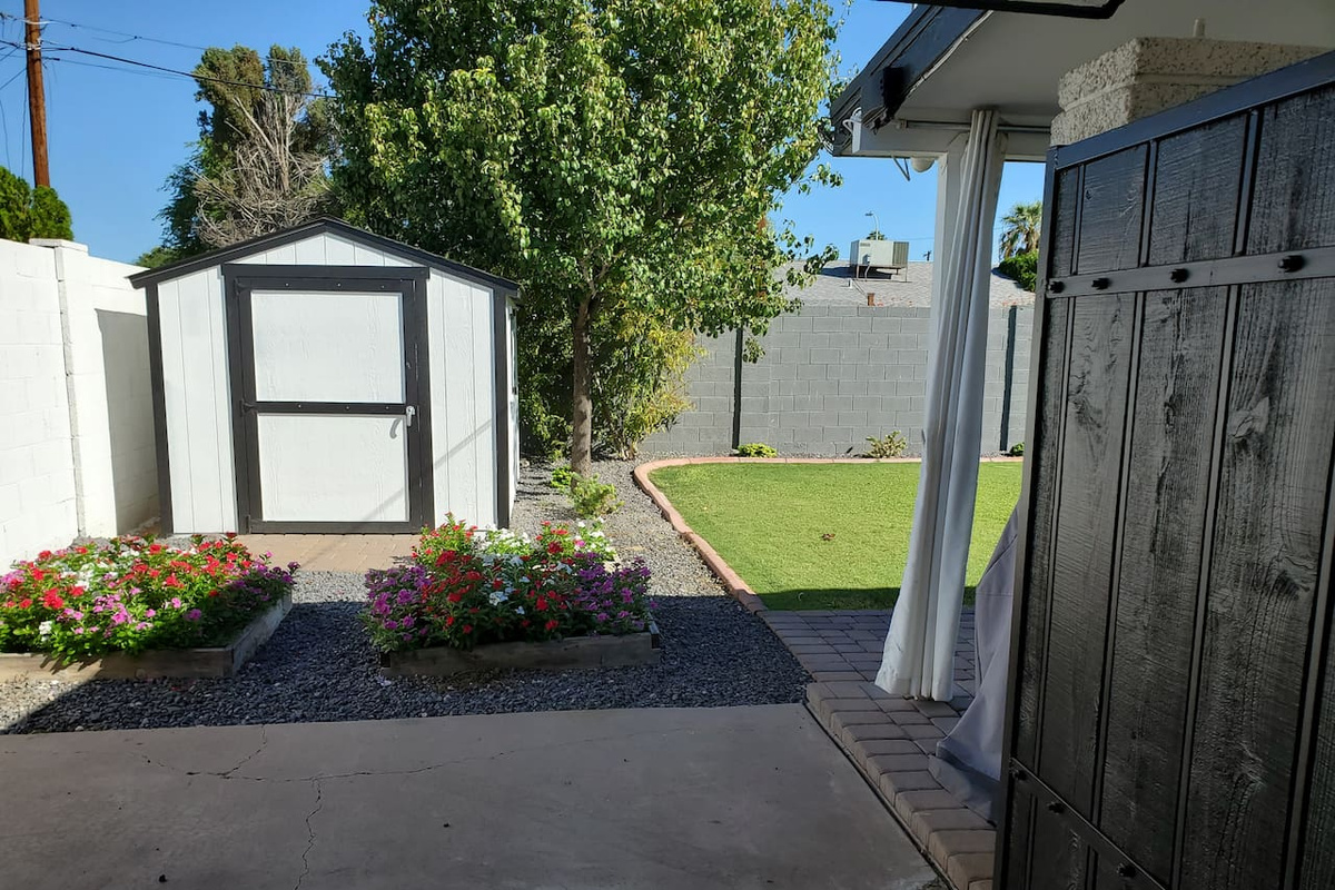 The yard is welcoming with trees, flowers, and green grass.