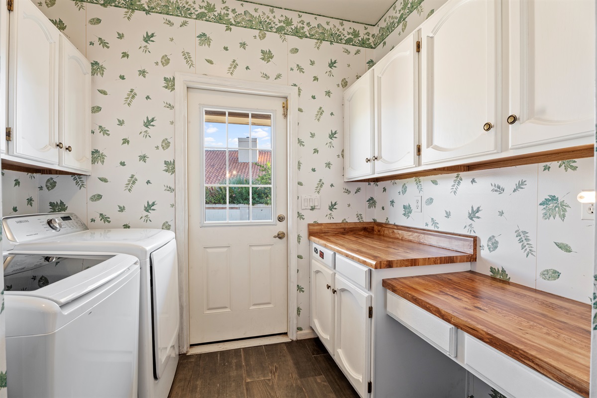 Fresh and functional, the laundry room pairs charming wallpaper with updated appliances and access to the outdoors.