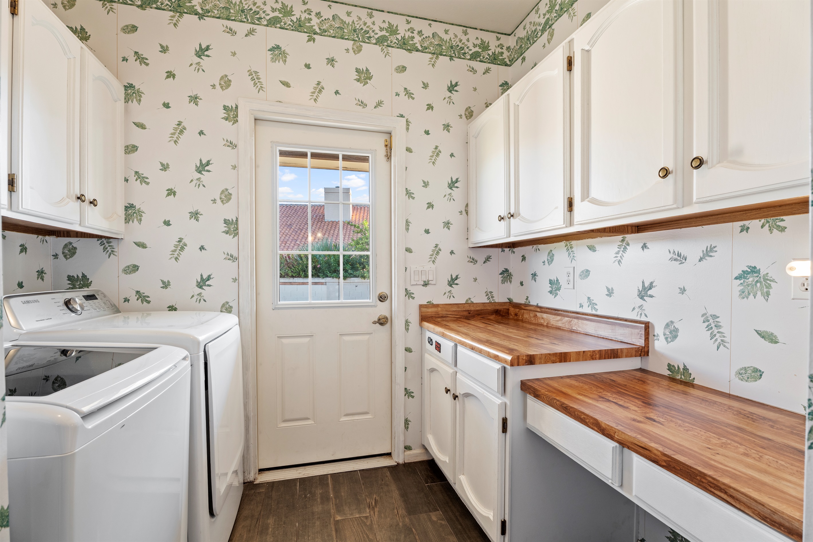 Fresh and functional, the laundry room pairs charming wallpaper with updated appliances and access to the outdoors.