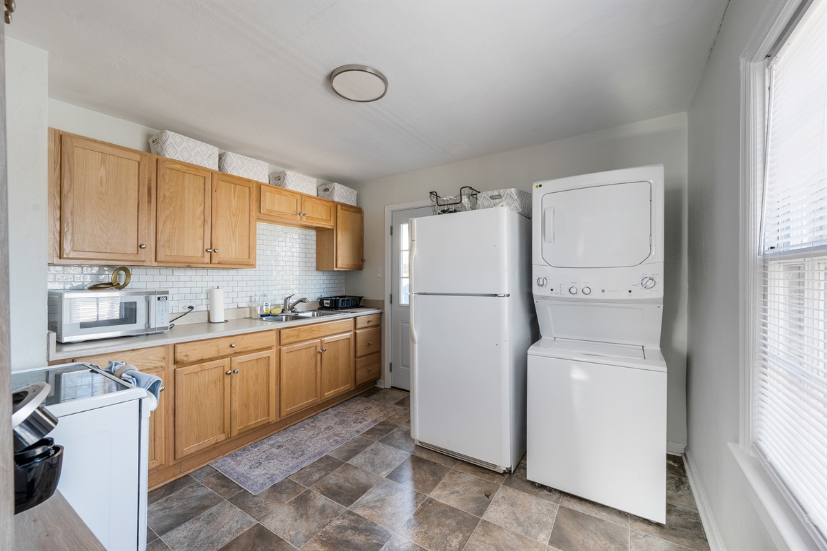 Fully equipped kitchen with everything you need, including a stove/oven, refrigerator, microwave, air fryer, blender, cookware, and a coffee bar stocked with coffee, creamer, and sugar. Stackable washer and dryer included.