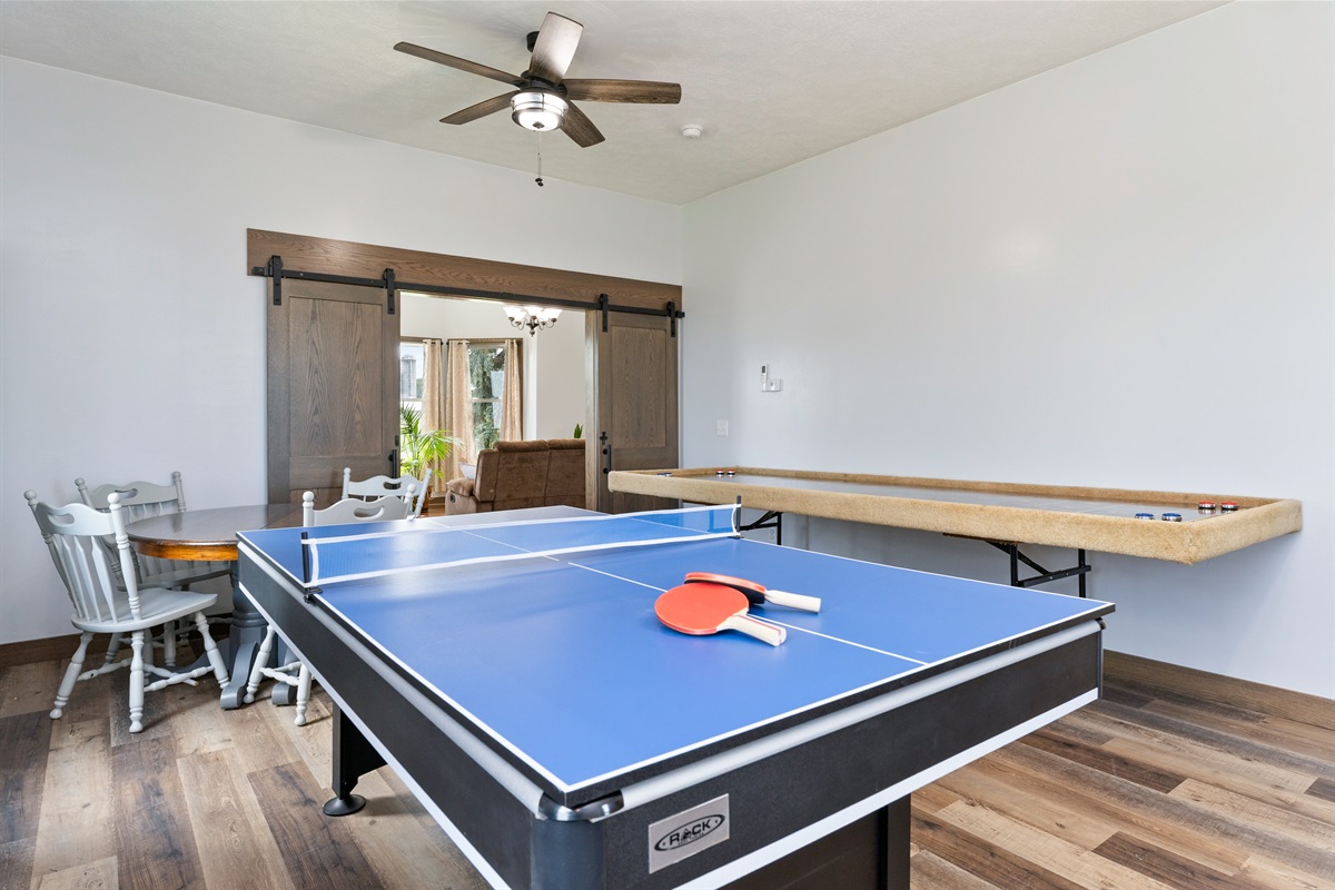 Entertainment-ready game room featuring a combination ping pong/pool table, shuffleboard, and air hockey with several board games and Cornhole for outside..... endless fun!