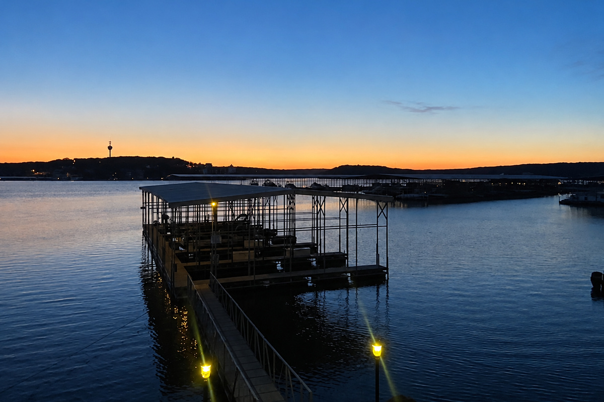 Illuminated dock extending over the water at sunset