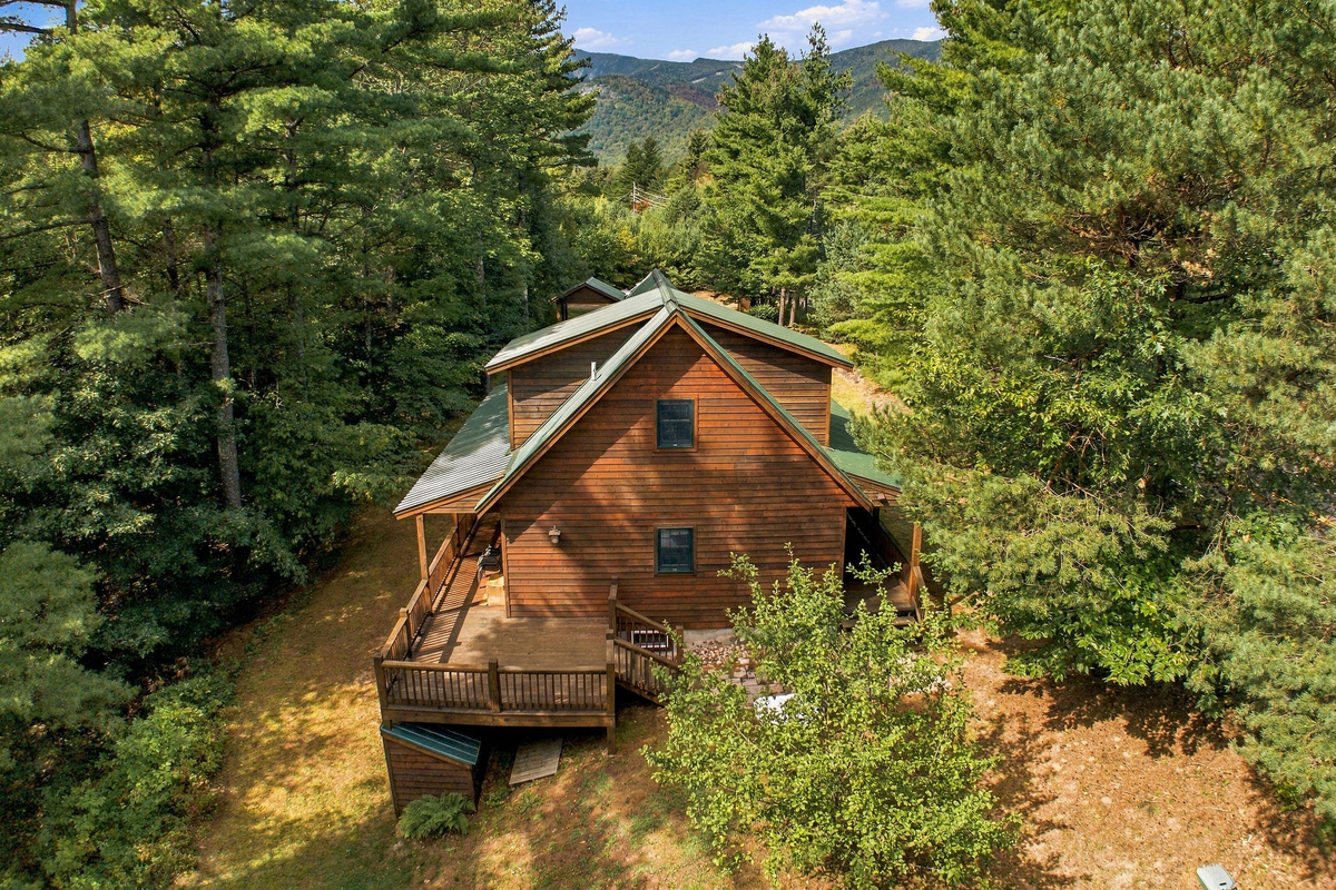 An aerial view reveals the lodge tucked into the beautiful Adirondack forest with impressive Whiteface Mountain in the background.