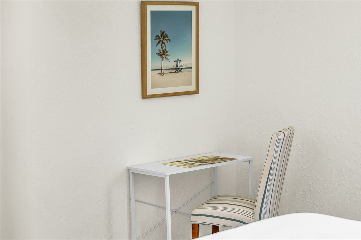 A cozy workspace tucked into Bedroom 3 offers the perfect spot to catch up on emails or plan your next beach day, featuring a minimalist desk set up and calming coastal decor