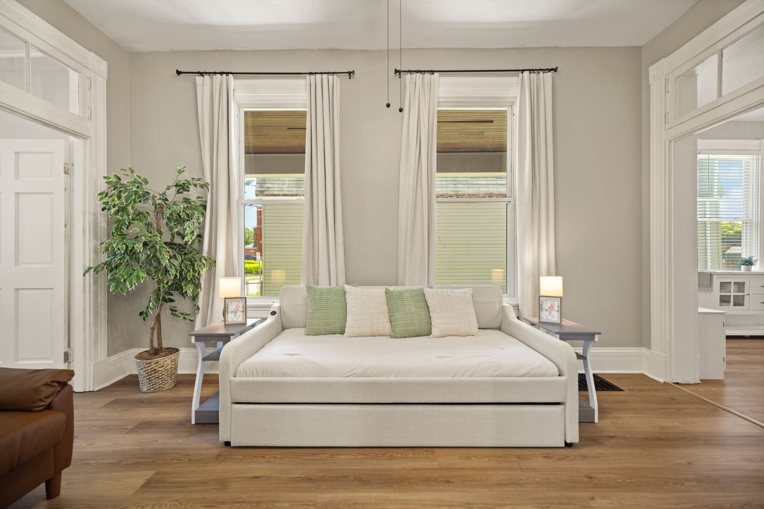 Light-filled living room with plush daybed with twin trundle underneath, warm hardwood floors, and bright natural light