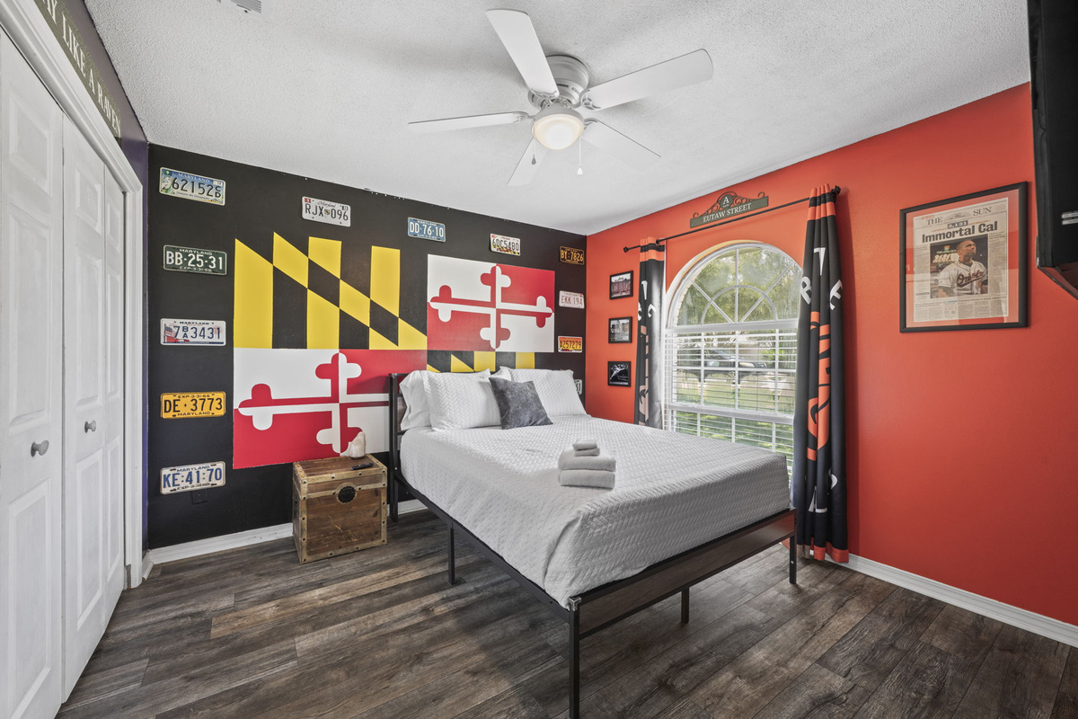 A bold, colorful bedroom with a hand-painted Maryland flag mural, vintage license plates, and sports memorabilia touches.
