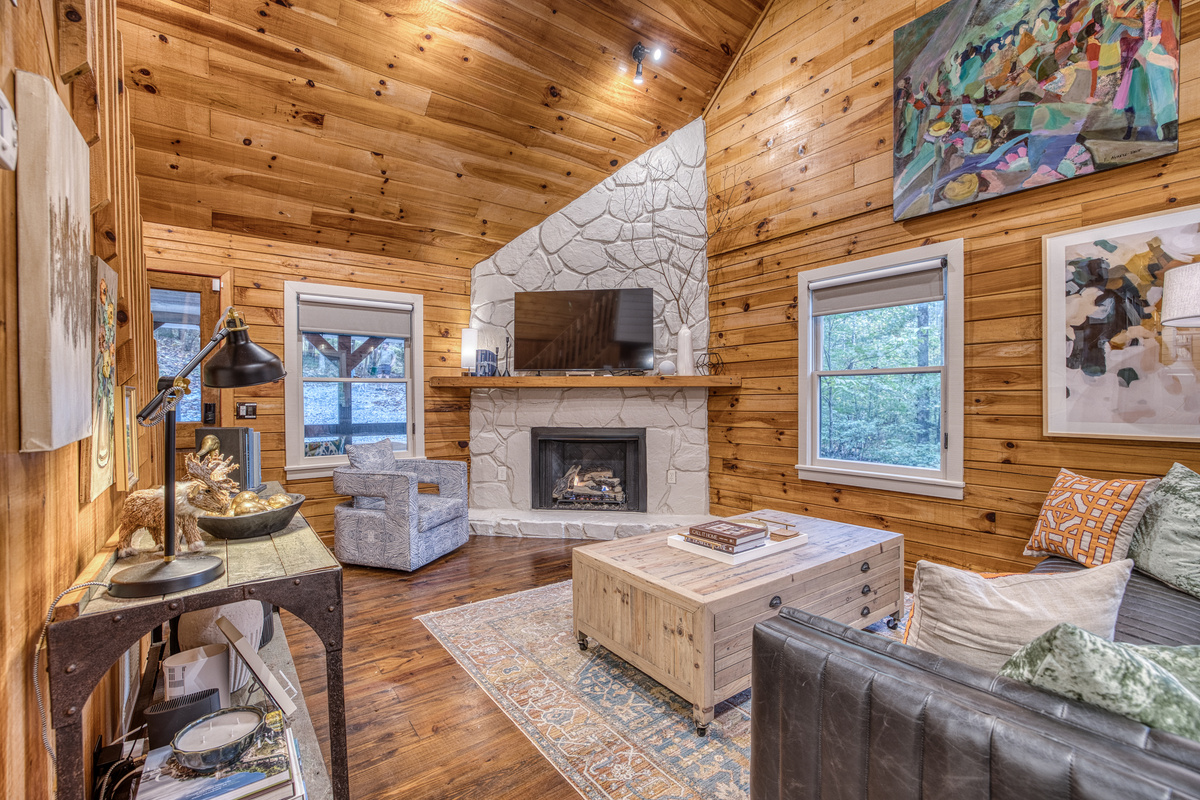 Living room with a stone fireplace and a TV.