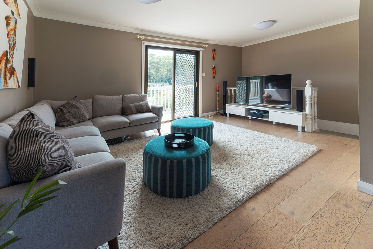 The upstairs living area at Luna’s Sanctuary features a comfortable sofa, large TV, sound system and sliding doors opening to the balcony.