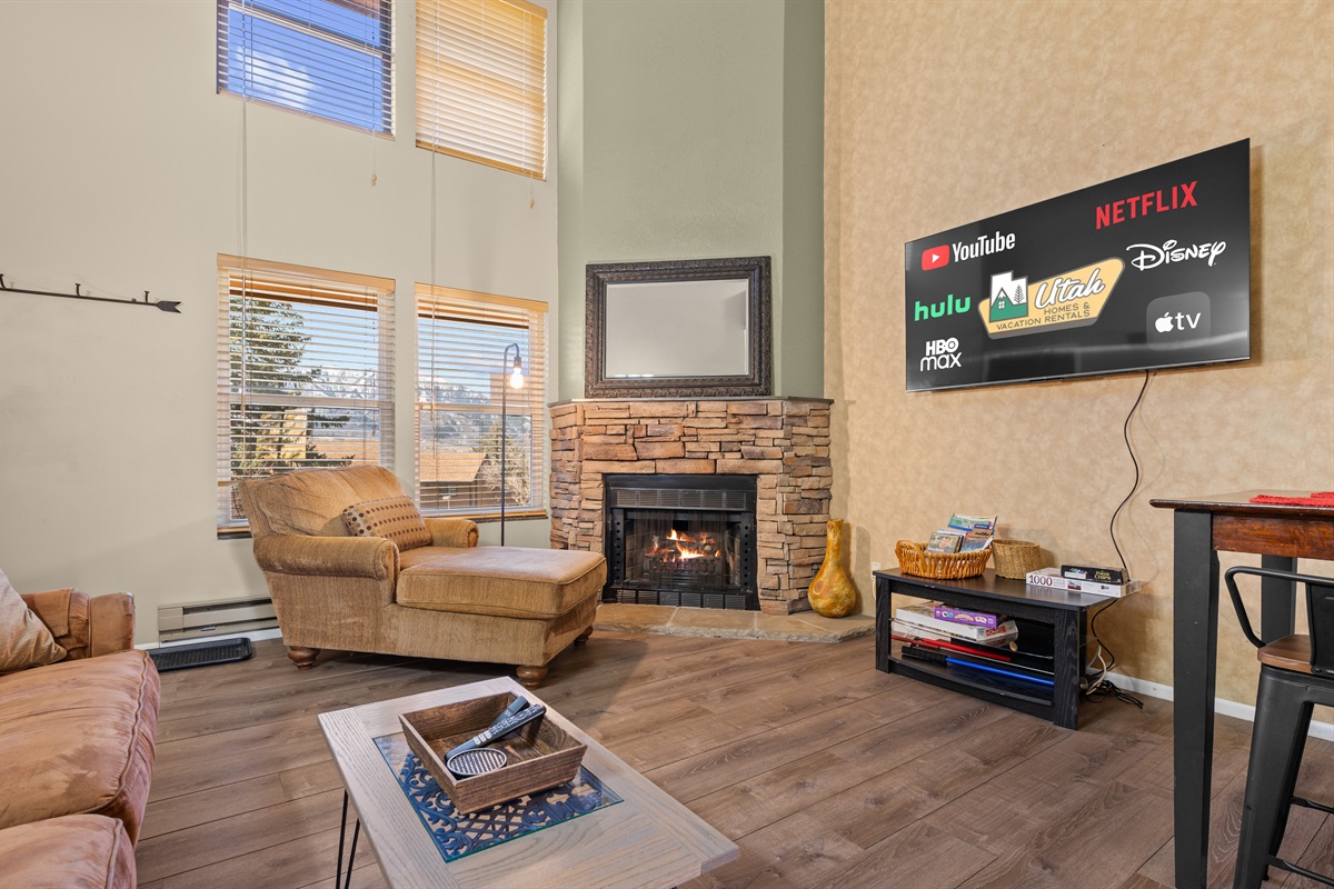 Bright living room with soaring ceilings, cozy fireplace, and large Smart TV for relaxing after a day of skiing or exploring the area.