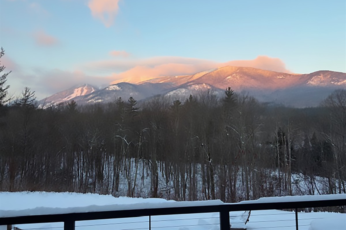 Golden-hour views of the Adirondack Mountains with Whiteface Mountain glowing in the distance—pure mountain serenity from the deck at Algonquin Mountain Chalet.