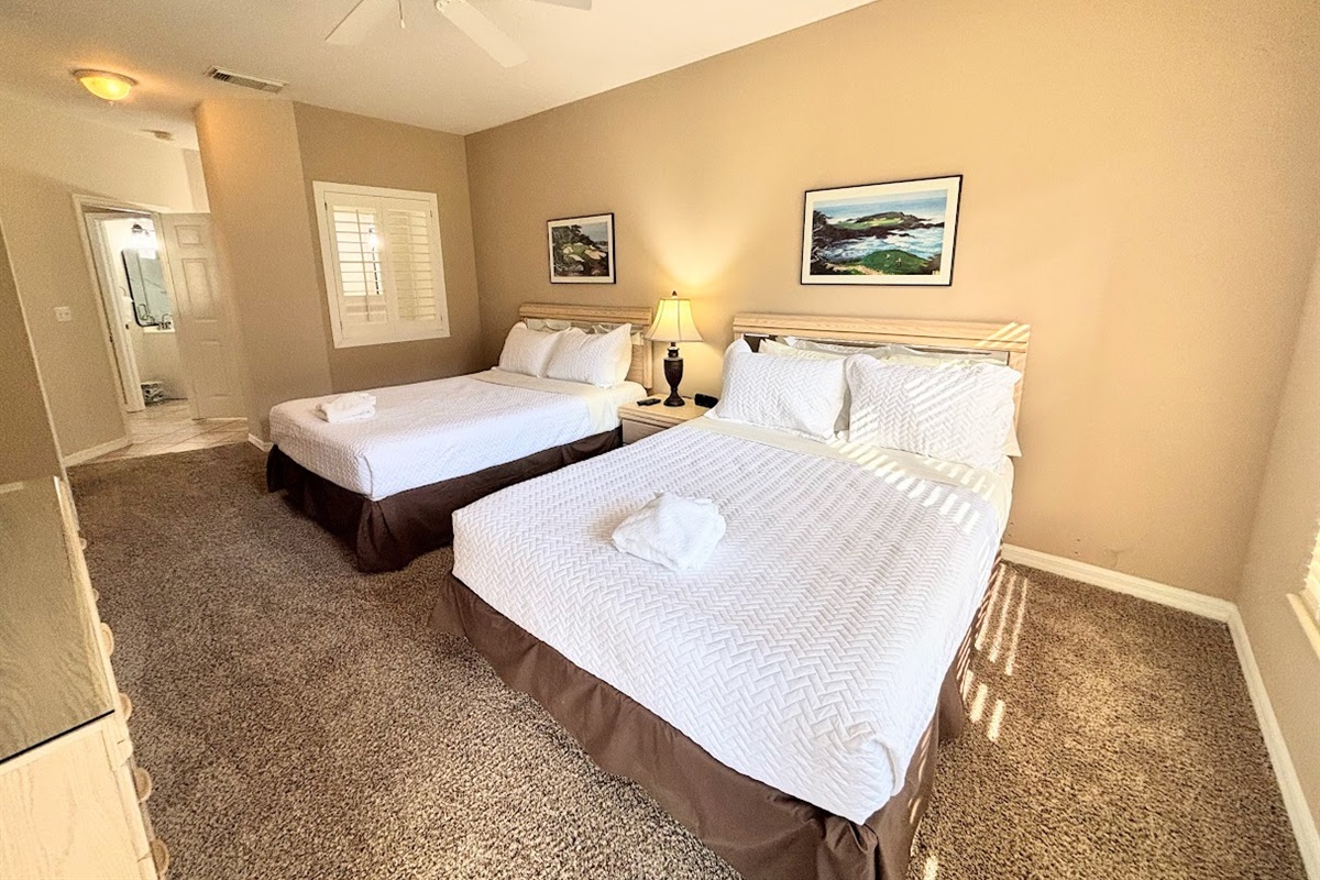 Bright bedroom featuring two beds, bedside lighting, and convenient access to the bathroom area.