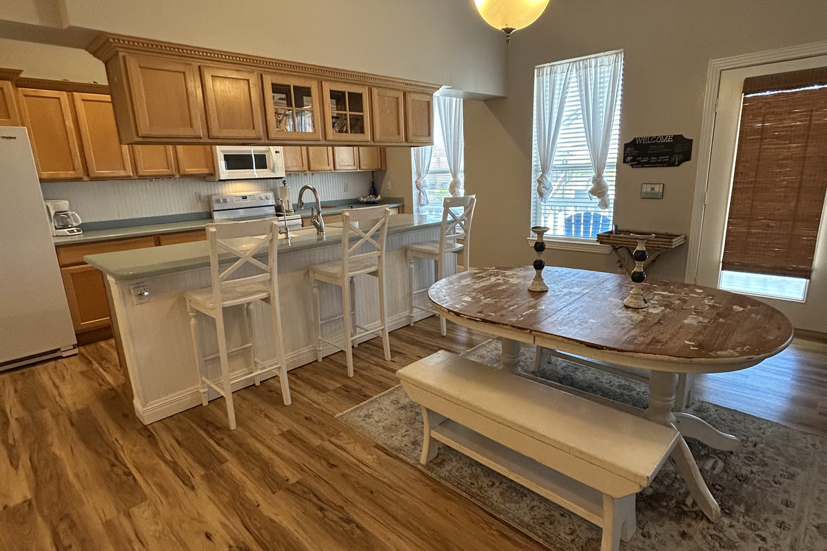 The spacious kitchen island provides extra prep space and casual seating for quick breakfasts or afternoon snacks. Just steps away, the farmhouse-style dining table with bench seating comfortably accommodates your group for memorable meals together.